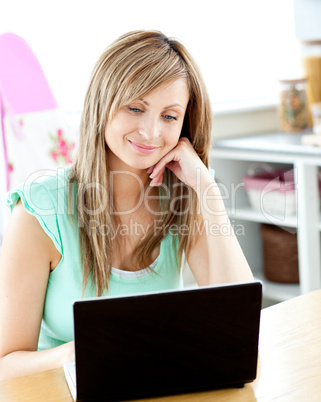 Kind caucasian woman using her laptop sitting in the kitchen