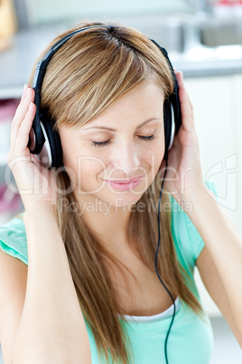 Young woman listening to music with headphones in the kitchen