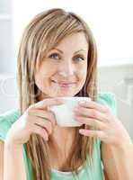 Charming young woman enjoy her coffee sitting in the kitchen