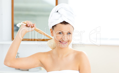 Lively woman washing her back smiling at the camera in the bathr