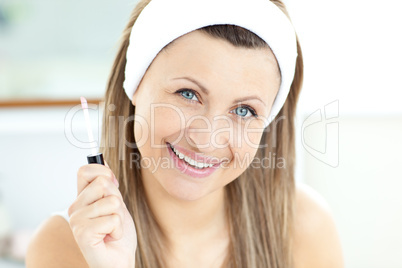 Smiling caucasian woman applying gloss on her lips in the bathro