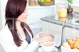 Positive businesswoman using her laptop during breakfast