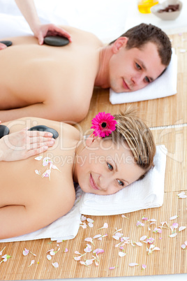 Jolly young couple receiving a back massage with hot stones
