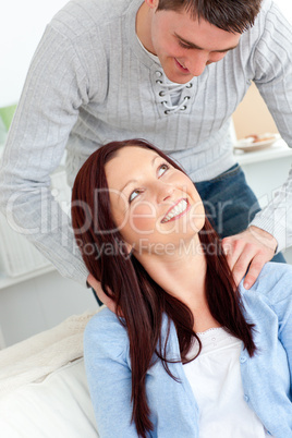 Kind boyfriend massaging his girlfriend's shoulders on the sofa