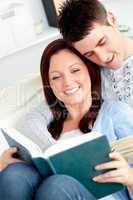 Happy couple reading a book in the living-room
