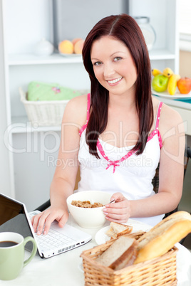 Pretty woman having breakfast in front of her laptop