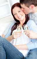 Attractive couple lying on the sofa and drinking champagne