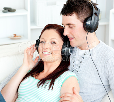 Charming couple listening to music with headphones lying on the