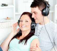 Charming couple listening to music with headphones lying on the