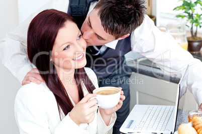 Handsome businessman kissing his bright girlfriend while having