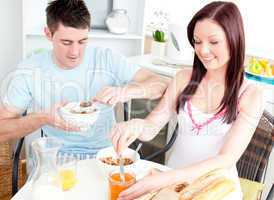 Delighted caucasian couple having breakfast in the kitchen