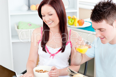 Bright couple using a laptop while breakfast