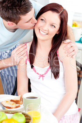 Attentive businessman kissing his girlfriend at her cheek during