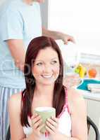 Attractive woman eating her breakfast at home holding a cup of c