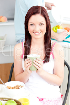 Charming woman eating her breakfast at home holding a cup of cof