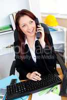 Cheerful businesswoman talking on phone and using her computer