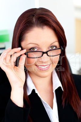 Serious businesswoman holding her glasses sitting in her office