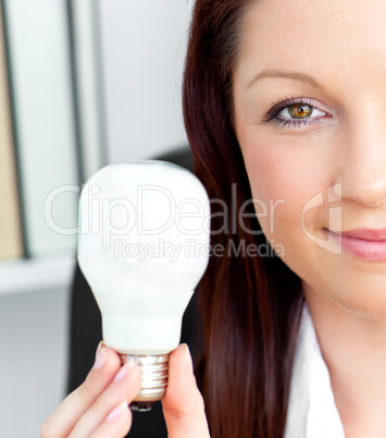 Confident young businesswoman holding a light bulb looking at th