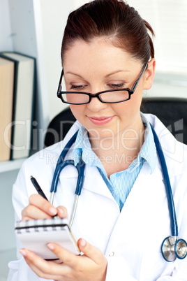 Serious female doctor smiling at the camera holding a notepad in