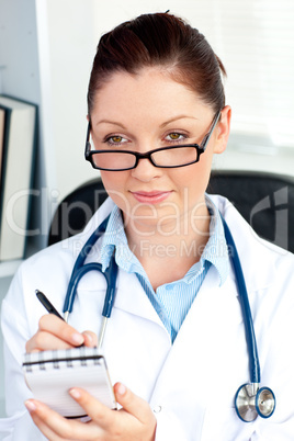 Concentrated female doctor smiling at the camera holding a notep