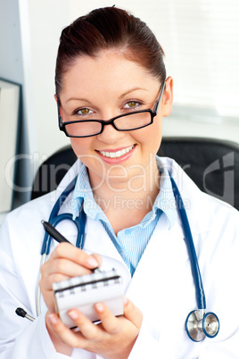 Self-assured female doctor smiling at the camera holding a notep