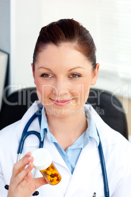 Close-up of a smiling female doctor holding pills in her office