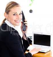 Happy young businesswoman talking on phone looking at the camera