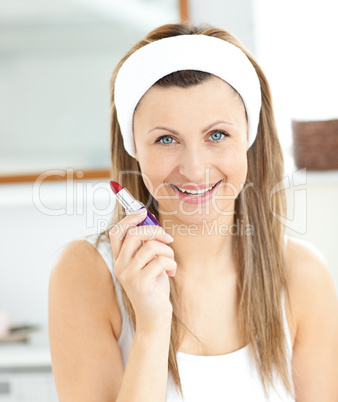 Delighted young woman using a red lipstick in the bathroom