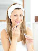 Bright woman applying gloss on her lips in the bathroom