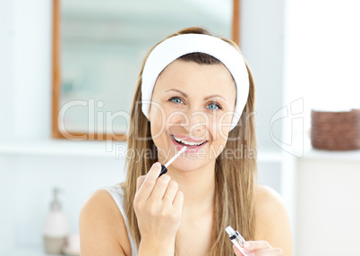 Radiant woman applying gloss on her lips in the bathroom