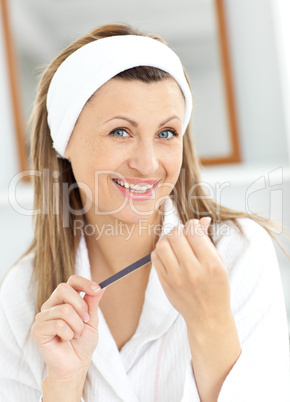 Cheerful woman filling her nails in the bathroom