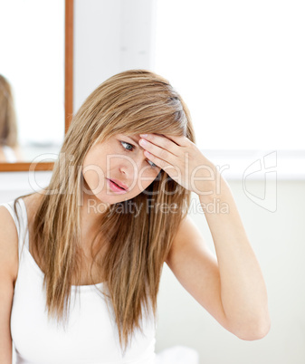 Depressed woman with a headache looking at the camera in the bat