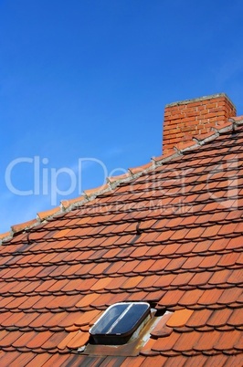 Dachfirst mit roten Dachiegeln, Fenster und Schornstein