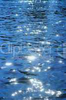 Lichtreflektionen auf einem See mit Wellen in Blau