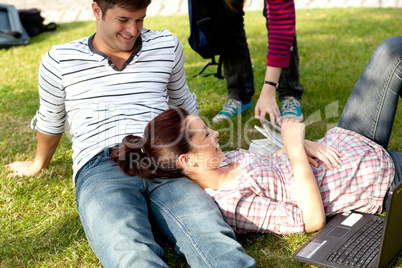 Couple of bright students lying on the grass