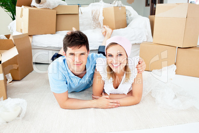 Jolly couple lying on the floor between boxes