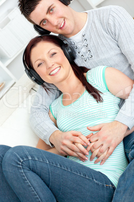 Attractive couple listening to music with headphones lying on th