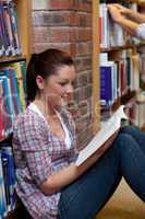 Pretty young woman reading a book sitting on the floor