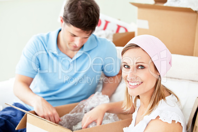 Ambitious young couple unpacking boxes with glasses