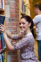 Charming young woman looking for a book