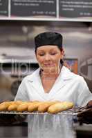 Cute young baker smelling baguettes