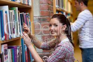 Joyful young woman looking for a book