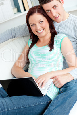 Loving couple using a laptop on a sofa Loving couple using a laptop on a sofa