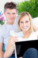 Enamored couple lying on the sofa with a laptop and a card