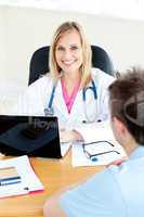 Smiling female doctor using her laptop and talking to her male p