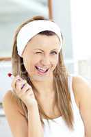 Delighted young woman using a red lipstick in the bathroom
