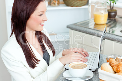 Positive businesswoman using her laptop during breakfast