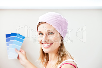 Joyful young woman choosing color for painting a room
