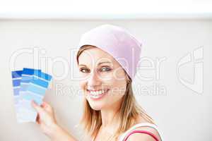 Joyful young woman choosing color for painting a room