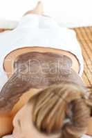 Young caucasian woman lying on a massage table with mud on her b
